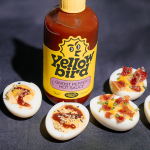 4 spicy deviled eggs with a bottle of Yellowbird Organic Ghost Pepper Hot Sauce