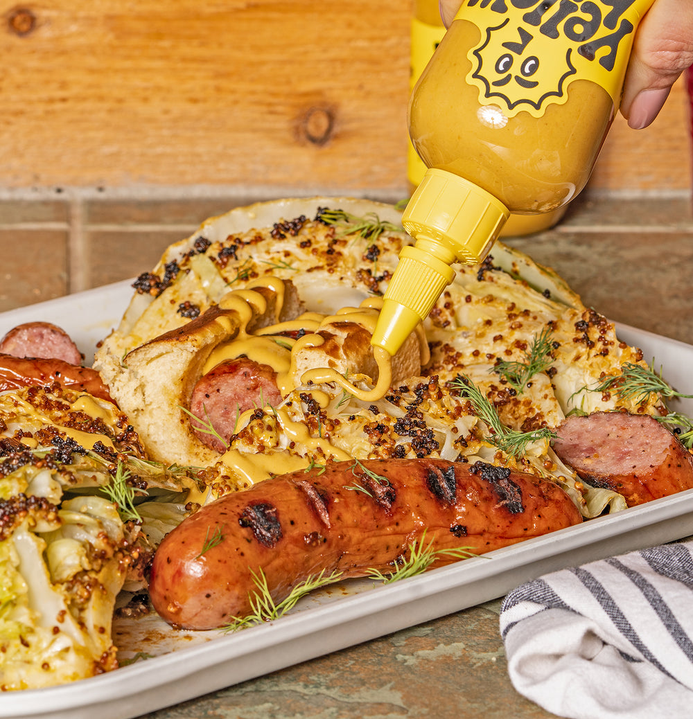 Yellowbird Garlic Shiitake hot sauce drizzled on top of bratwurst and sautêed cabbage